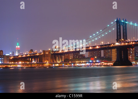 New York City-Nacht-Szene mit Manhattan Bridge und Empire State Building. Manhattan verbindet New York und Brooklyn. Stockfoto