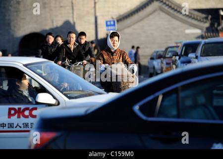 Leute Fahrt Fahrräder oder Elektro-Fahrräder auf den Straßen voller Autos in Peking, China. 9. März 2011 Stockfoto