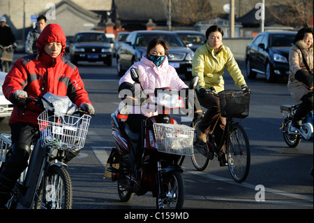 Menschen fahren Fahrrad oder e-Bikes auf den Straßen voller Autos in Peking, China. 9. März 2011 Stockfoto