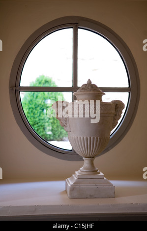 Klassische griechische Urne auf dem Sims ein rundes Fenster Stockfoto