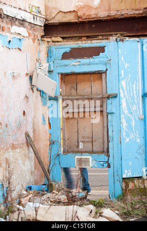 Ein Mann geht vorbei an einer Tür auf einer verlassenen abgerissen-Shop in Loughborough, Leicestershire, UK. Stockfoto