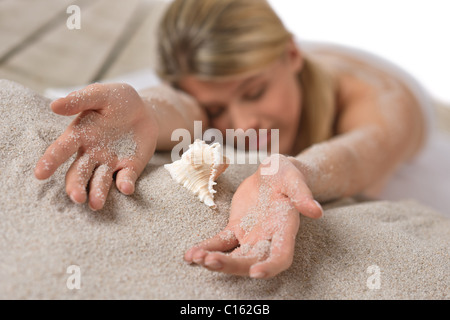 Strand - Frau mit Seesternen liegen im Sand Sonnen Stockfoto