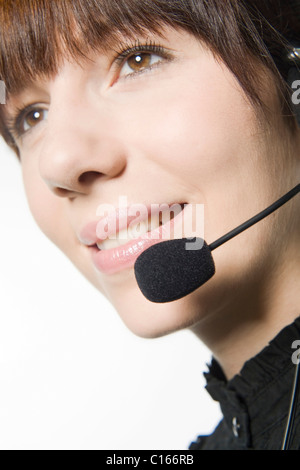 Junge, dunkelhaarige Frau am Telefon mit einem Kopfhörer Stockfoto