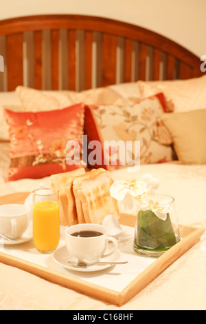 Frühstückstablett mit Kaffee, Toast und Orangensaft auf einem Luxus-Bett Stockfoto