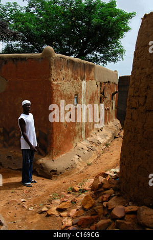 Junger Mann stehen in einer engen Gasse zwischen den festungsartigen Häusern in Tiebele, Burkina Faso, Westafrika Stockfoto