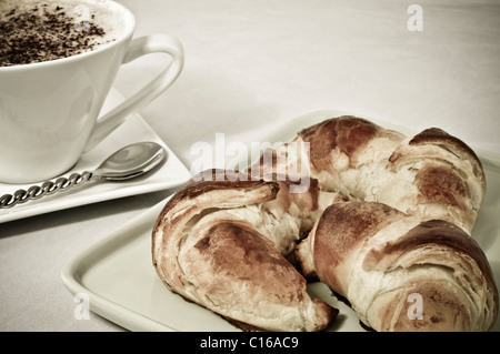 Perfektes Frühstück - Cappuccino in weiße Tasse und hausgemachten Croissants - abstrakte alte Foto-Effekt Stockfoto