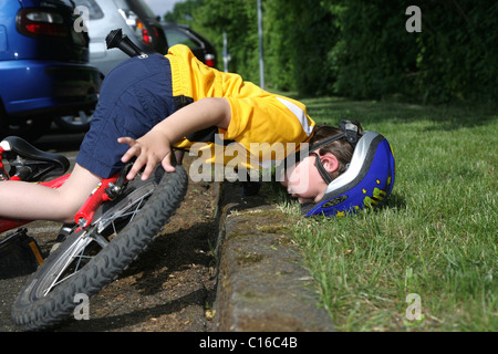 Five-Year-Old Boy das Tragen eines Helms beim Radfahren Sturz von seinem Fahrrad gestellt Foto Stockfoto