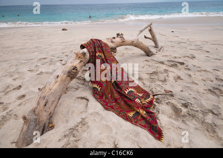 Eine Batik-Sarong drapiert über Login-Treibholz am Strand von Tegal Bias in Padang Bai Bali Indonesien Stockfoto