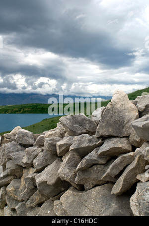 Steinmauer mit Berg, Steinmauer auf einer Halbinsel zwischen der Straße und Weide für Schafe Stockfoto