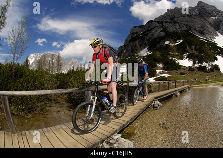 Mountainbiker auf einer Holzbrücke auf See Seebensee, Ehrwald, Tirol, Austria, Europe Stockfoto