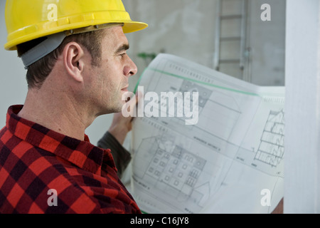 Arbeiter mit harten Helm, Blick auf einen Bauplan Stockfoto