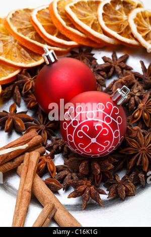 Weihnachtskugeln, Sternanis, Zimtstangen und getrocknete Scheiben auf einen Teller orange Stockfoto