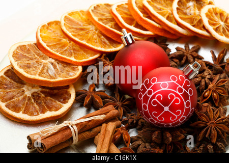 Weihnachtskugeln, Sternanis, Zimtstangen und getrocknete Scheiben auf einen Teller orange Stockfoto