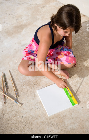 Mädchen malen auf Leinwand am Boden sitzen Stockfoto