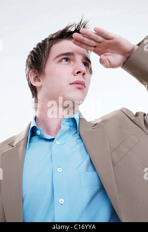 Junger Geschäftsmann hält seine Hand auf seine Stirn, seine Augen vor der Sonne schützen Stockfoto