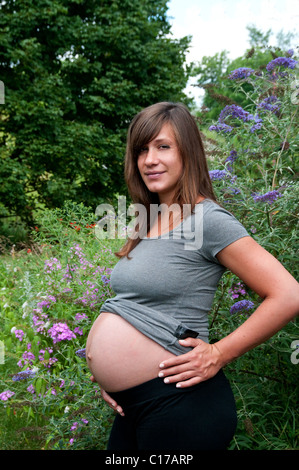 Kate Burns; Schöne junge schwangere Frau; im Freien vom Schmetterlingsstrauch; Bauch-Shot; Model Release 20100719KB 19820629 Stockfoto