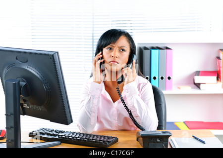 Junge schwarze Business Frau Multitasking mit zwei Handys in office Stockfoto