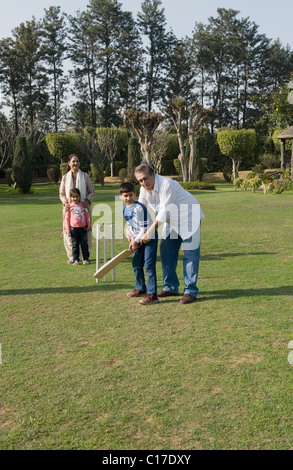 Familie spielen Cricket in Rasen Stockfoto