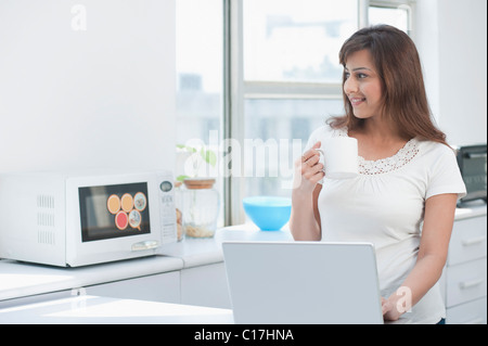 Frau mit einem Laptop in der Küche Stockfoto