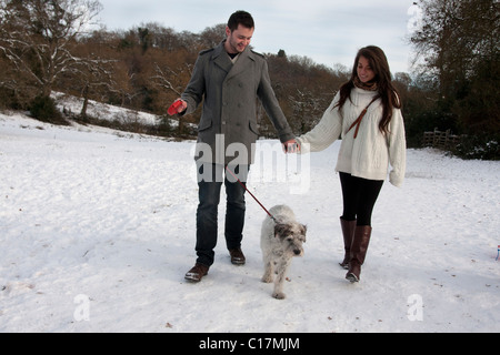 junges Paar walking Hund im Schnee Stockfoto