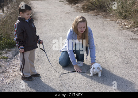 junge Frau, die kleinen Jungen Haustier Baby Kaninchen an der Leine laufen Stockfoto