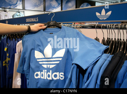 Ein Mitarbeiter halten ein T-shirt mit dem Adidas-Logo in ein Outlet-Store von der Adidas-Salomon AG in Herzogenaurach, Bayern Stockfoto
