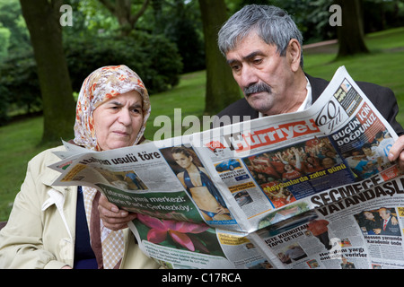 Älteren türkischen Ehepaar Lesen einer Zeitung in einem Park, Herne, Deutschland Stockfoto