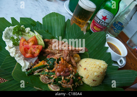 Langsam gekochter balinesischer Hähncheneintopf namens Ayam Betutu mit Reis und Salat serviert auf grünen Bananenblättern Stockfoto