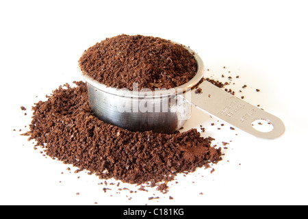 Gemahlener Kaffee verschütten aus einer vollen Kaffee Maßnahme. Schuss auf weißem Hintergrund. Schwerpunkt liegt auf den Rand der Tasse. Stockfoto