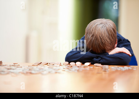 Kopf des jungen auf Armen umgeben von Münzen Stockfoto