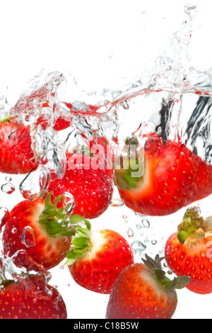 Foto von Erdbeeren fallen ins Wasser vor einem weißen Hintergrund. Bewegungsunschärfe. Stockfoto