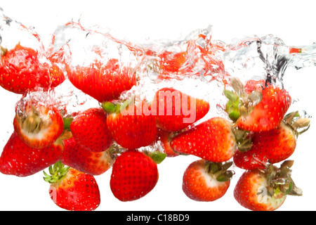 Foto von Erdbeeren fallen ins Wasser vor einem weißen Hintergrund. Bewegungsunschärfe. Stockfoto