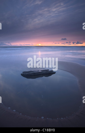 Die untergehende Sonne bietet eine bunte Kulisse zum Sandstrand im Dunraven Bay in der Nähe von Southerndown auf Glamorgan Heritage Stockfoto