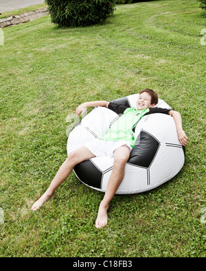 Entspannen Sie sich auf aufgeblasenen riesigen Fußball junge Stockfoto