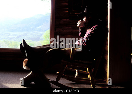 USA, Wyoming, Cody, dude Ranch, Double Diamond X Ranch, Wrangler in einem Schaukelstuhl mit einem Becher Stockfoto