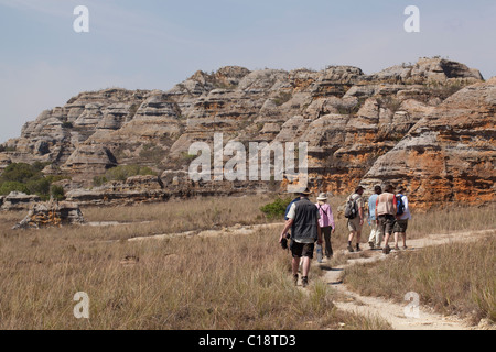 Trekking durch Isalo Nationalpark, Madagaskar, vor dem Hintergrund der Jurassic Sandstein Touristen erodierten Klippen. Stockfoto