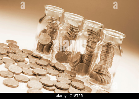 Glas Gläser voller Münzen, überschüssige Münzen beiseite Stockfoto