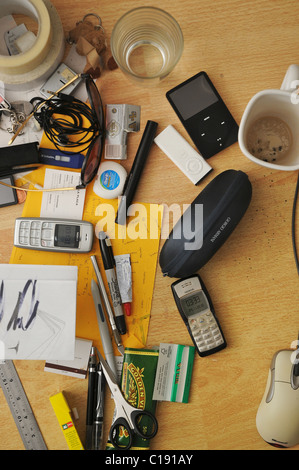 Senkrechten Blick auf einen unordentlichen Schreibtisch-Oberfläche mit allen Arten von Schreibwaren, Elektronik und schmutzige Tassen. Stockfoto