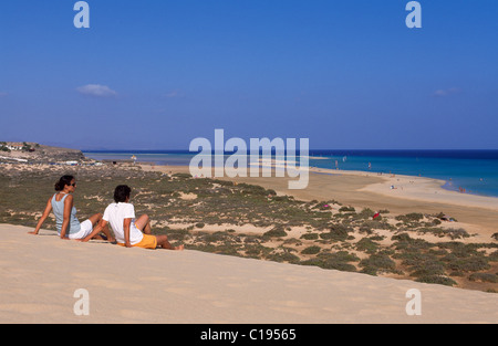 Ein paar sitzt auf einer Düne mit Blick auf die Playas de Sotavento Strand, Fuerteventura, Kanarische Inseln, Spanien, Europa Stockfoto