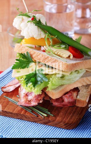Speck und Käse-Sandwich, garniert mit frischem Gemüse Stockfoto