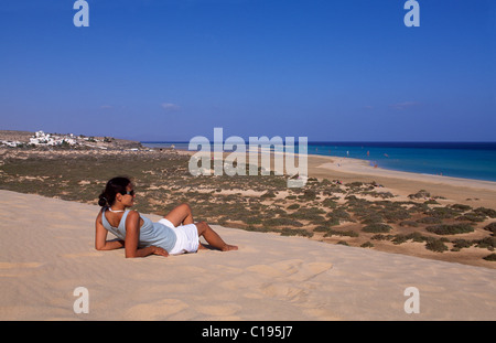 Frau liegt auf einer Düne mit Blick auf den Strand von Playas de Sotavento auf Fuerteventura, Kanarische Inseln, Spanien, Europa Stockfoto