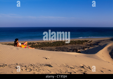 Frau liegt auf einer Düne mit Blick auf den Strand von Playas de Sotavento auf Fuerteventura, Kanarische Inseln, Spanien, Europa Stockfoto