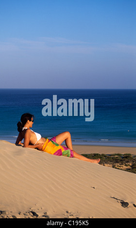 Frau liegt auf einer Düne mit Blick auf den Strand von Playas de Sotavento auf Fuerteventura, Kanarische Inseln, Spanien, Europa Stockfoto