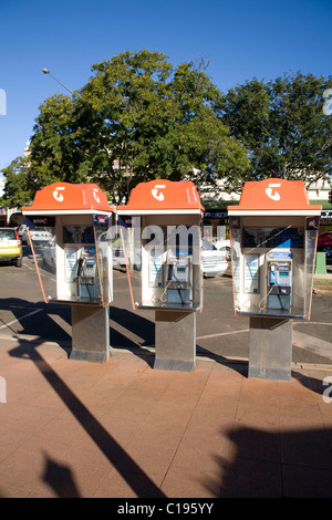 Eine Reihe von Münztelefonen mit orangefarbenen Hauben in einer Straßenlage unter klarem blauem Himmel Stockfoto