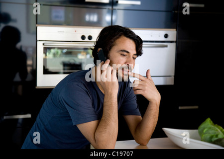 Mann auf seinem Handy in der Küche telefonieren Stockfoto