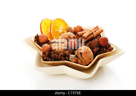 Weihnachts-Dekoration, Waltnuts, getrocknete Orangenscheiben, Cinnammon Stangen, Marzipan-Kartoffeln und Sternanis in einer sternförmigen Schüssel Stockfoto