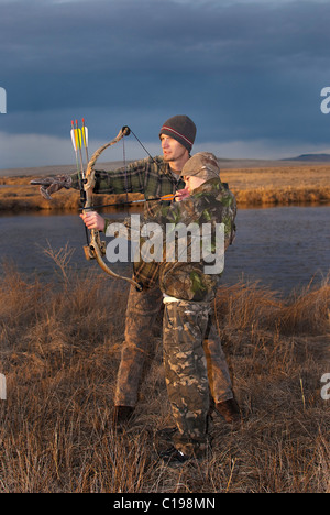 Ein kleiner Junge und sein Vater lernen Bogenjagd. Stockfoto