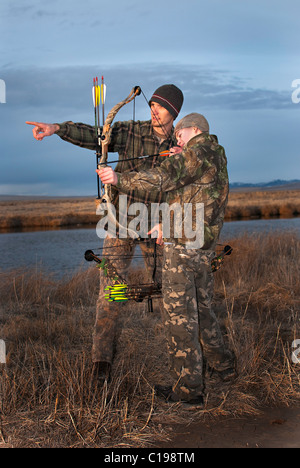 Ein kleiner Junge und sein Vater lernen Bogenjagd. Stockfoto