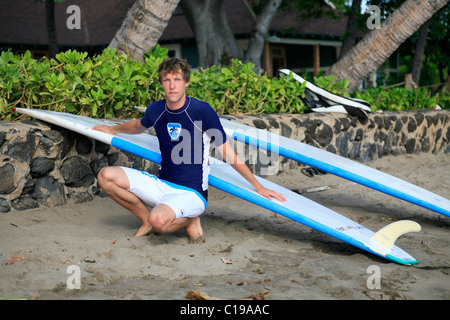 Surfer tragen Boardshorts und Surfshirt sitzt vor seinem Longboards, Lahaina, Maui, Hawaii, USA Stockfoto