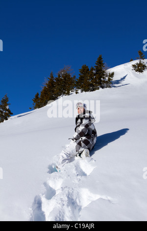 Einsames Mädchen im Schnee sitzen und ausruhen Stockfoto